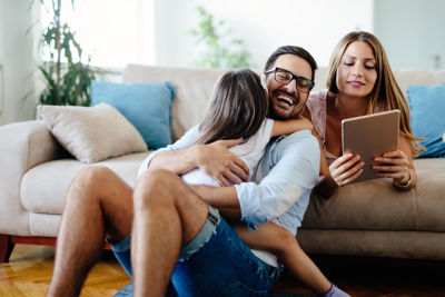 Man hugging child on floor in front of woman on sofa smiling