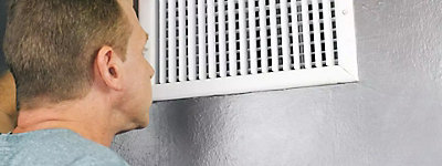 Man examining duct through a vent - Williams Comfort Air Heating, Cooling, Plumbing & More