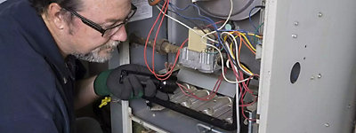 Technician checking a heating issue on furnace - Williams Comfort Air Heating, Cooling, Plumbing & More