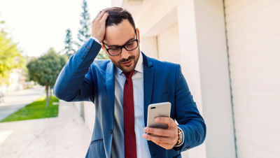 Man looking at smartphone while grabbing head