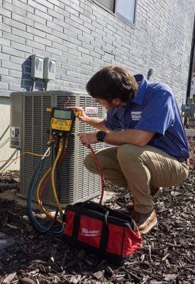 Technician outside testing a customer's heat pump