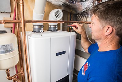 Coolray plumber working on tankless water heater smiling