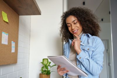 Smiling african teen girl, afro american college student, ethnic school pupil, remote worker studying, distance learning holding notebook in hands, thinking, making notes working from home office.