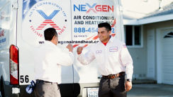 Two NexGen Techs at the back of a work van giving each other a fist bump