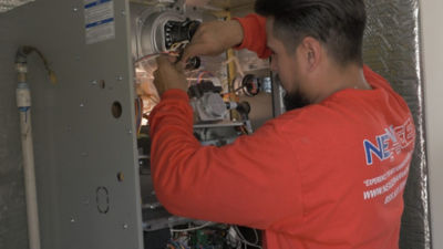 A NexGen employee working on a heating system