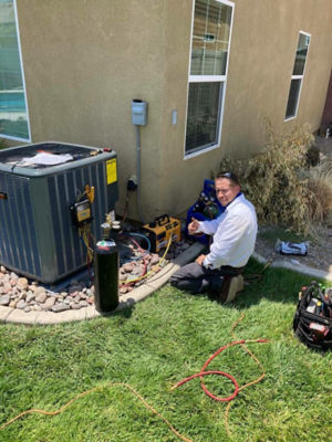 A man giving a thumbs up while working on an AC unit.