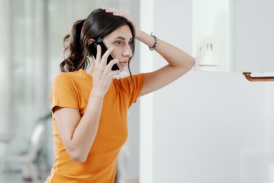 Worried woman calling a boiler breakdown service at home, her boiler is not working