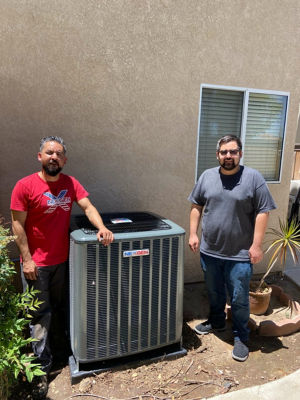 Two men standing next to a NexGen AC unit.