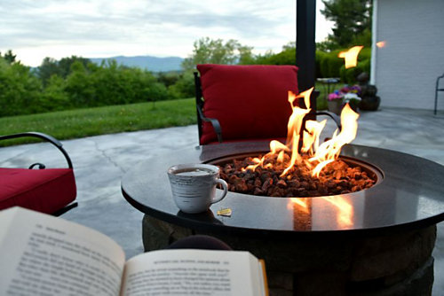 A fire pit with a cup of coffee and a book