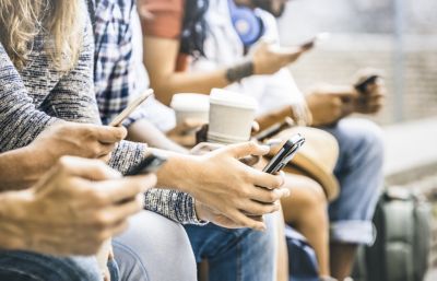 Several people sitting next to each other on smartphones