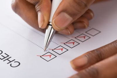 A persons hand check marking a box on a sheet of paper.