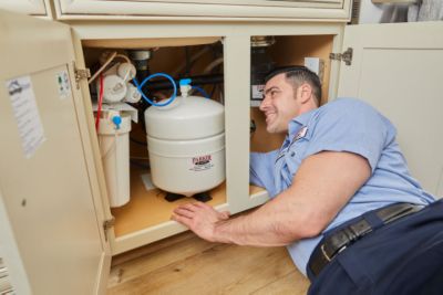 Parker and Sons technician under a kitchen sink installing a RO System