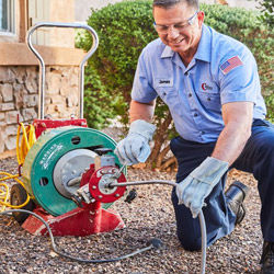 Collins Comfort plumber in the yard clearing a pipe