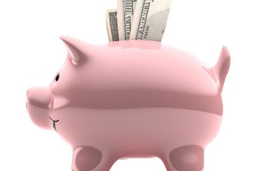 Pink porcelain piggy bank with cash sticking out of the top