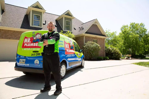 Smiling plumber stands in front of Mr. Plumber truck 