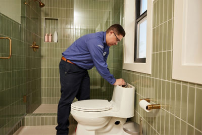 Plumber in bathroom repairing a toilet