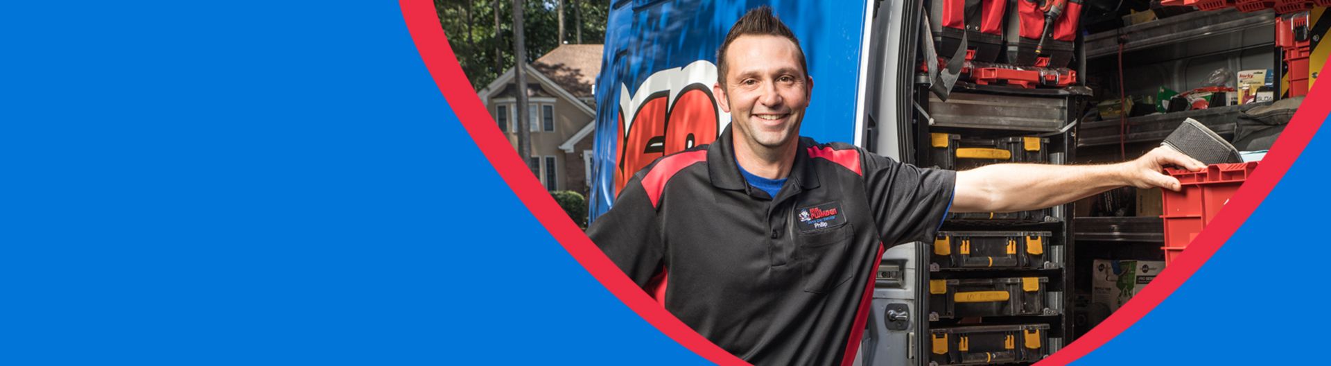 Plumber smiling next to equipment in van