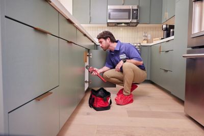 Plumber in kitchen working under the sink