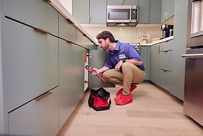 Plumber in kitchen working under the sink