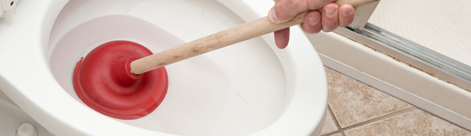 A person using a plunger to plunge a toilet