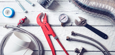 Assortment of plumbing tools spread out on wood table