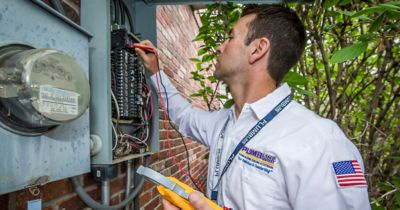 Plumbline electrician looking at wiring outside of house