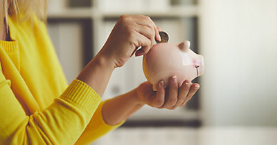 Woman putting coin into piggy bank