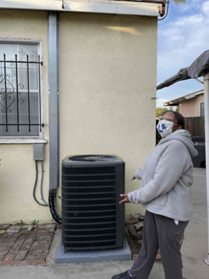 A woman pointing to an Air Conditioning Unit.