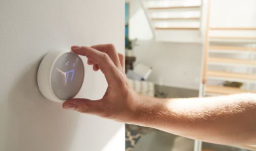 A hand pressing a digital thermostat