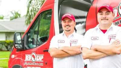 A couple of men standing in front of a red truck