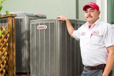 Red Cap HVAC tech standing next to a heat pump