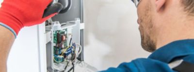 A tech wearing a red work glove is inspecting the a furnace