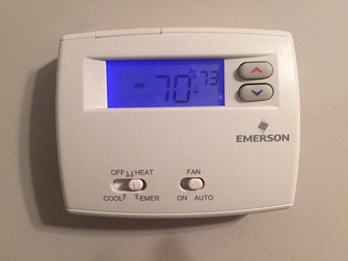 A white thermostat with a blue screen