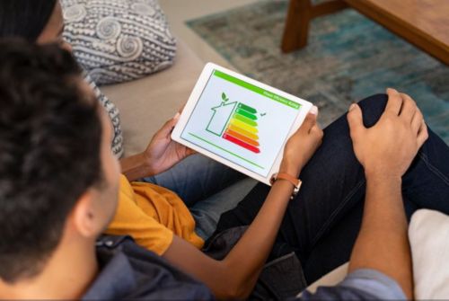 Family sitting on a couch looking at an energy app on tablet