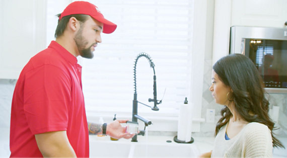 Red Cap plumber explaining to customer her faucet's problem