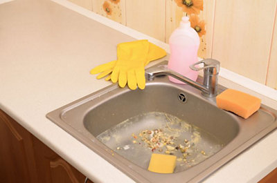 A Dirty Sink with Yellow Gloves and a Bottle of Soap