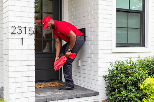 A Red Cap technician covering his shoes before entering a house