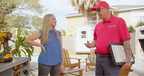Red Cap tech in branded polo talking to a customer in a backyard