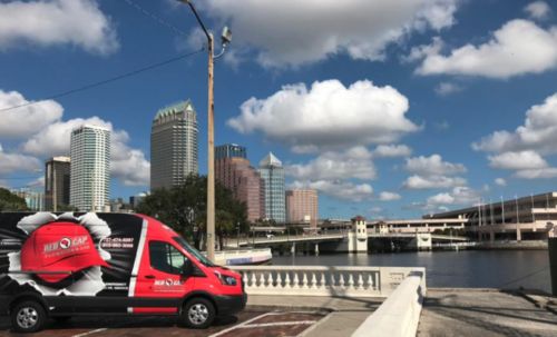 a red van on a street near a body of water