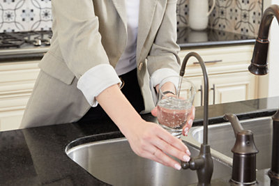 Woman get ro water from stainless faucet into a glass