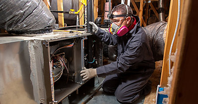 Service Champions technician inspecting furnace in attic