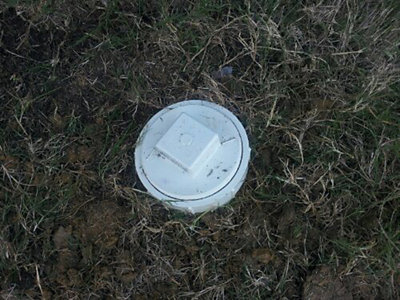 Top of covered sewer line showing above grass