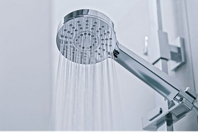 A water softener shower head that is on and water is coming out of it. 