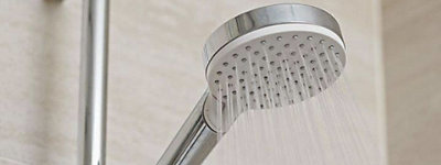 Close up of a stainless steel shower head that is spraying water