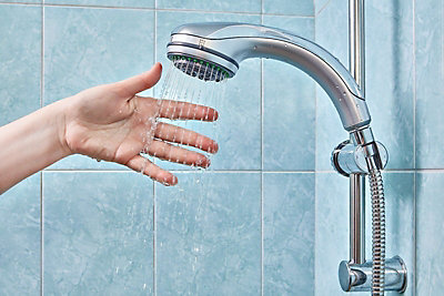 Hand feeling the shower water.