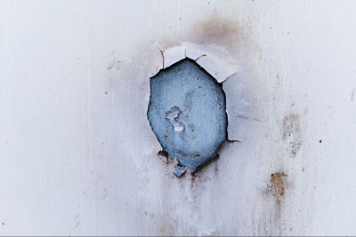 Damage from a slab leak showing a hole in a white wall with water stains and concrete exposed underneath - a common plumbing emergency in Dallas homes that requires professional repair.