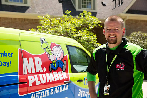 Smiling plumber stands in front of Mr. Plumber truck 
