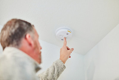 Man in his home checking his smoke detector