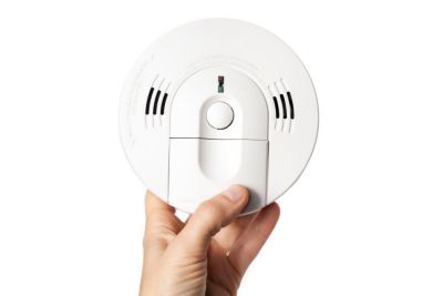 Smoke detector with carbon monoxide alarm in hand of homeowner or electrician. Hard wired with backup batterie. Fire safety product for homes, apartments, stores and buildings. Selective focus.