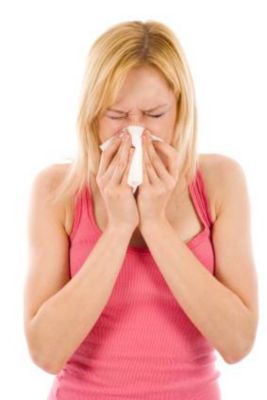 Woman in pink tank top sneezing into tissue